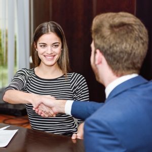 Smiling young couple shaking hands with an insurance agent or investment adviser